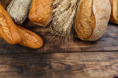 Tahta bir masada farklı somun ekmeği, buğday, un ve glüten.