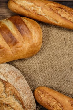 Tahta bir masada farklı somun ekmeği, buğday, un ve glüten.