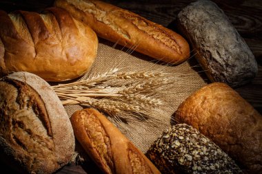 Tahta bir masada farklı somun ekmeği, buğday, un ve glüten.