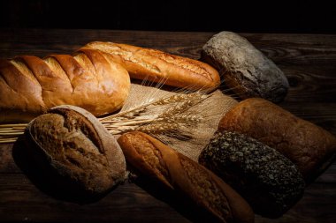 Tahta bir masada farklı somun ekmeği, buğday, un ve glüten.