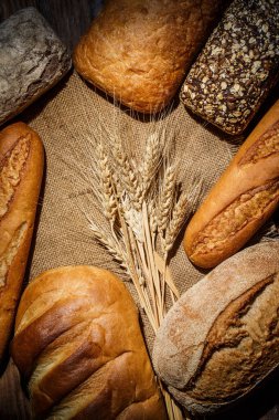 Tahta bir masada farklı somun ekmeği, buğday, un ve glüten.
