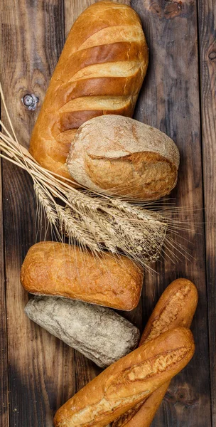 Różne Bochenki Smacznego Chleba Pszenicą Mąką Glutenem Drewnianym Stole — Zdjęcie stockowe