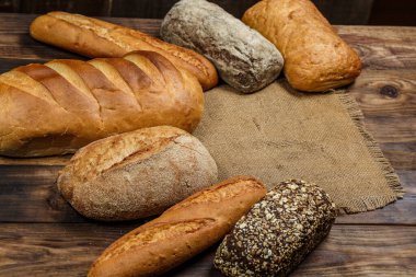 Tahta bir masada taze somun ekmek, buğday ve glüten.