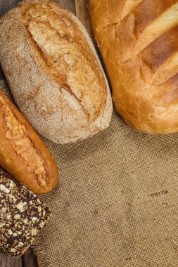 Tahta bir masada taze somun ekmek, buğday ve glüten.