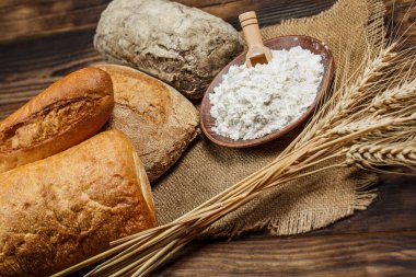 Tahta bir masada taze somun ekmek, buğday ve glüten.