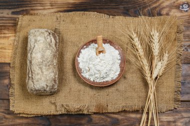 Tahta bir masada taze somun ekmek, buğday ve glüten.
