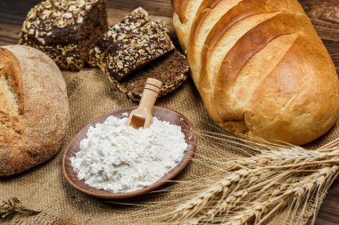 Tahta bir masada taze somun ekmek, buğday ve glüten.