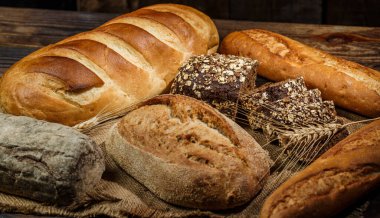 Tahta bir masada taze somun ekmek, buğday ve glüten.