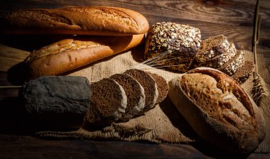 Tahta bir masada taze somun ekmek, buğday ve glüten.