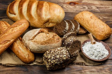 Tahta bir masada taze somun ekmek, buğday ve glüten.