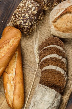 Tahta bir masada taze somun ekmek, buğday ve glüten.