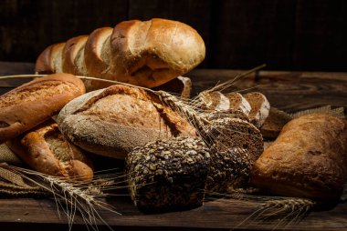 Tahta bir masada taze somun ekmek, buğday ve glüten.