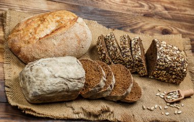 Tahta bir masada taze somun ekmek, buğday ve glüten.