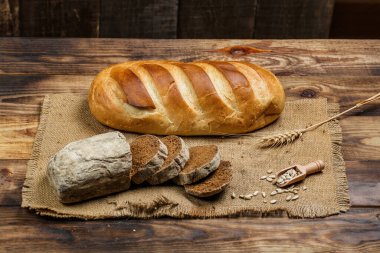Tahta bir masada taze somun ekmek, buğday ve glüten.