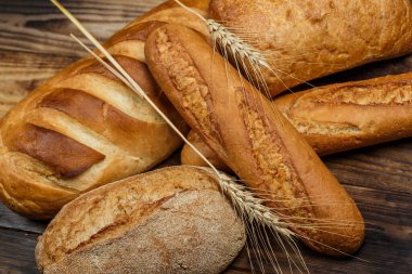 Farklı somun ekmeği un ve glütensiz buğdayla ahşap bir masada pişirilir.