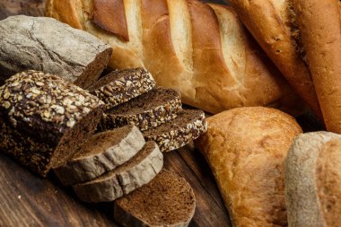 Farklı somun ekmeği un ve glütensiz buğdayla ahşap bir masada pişirilir.