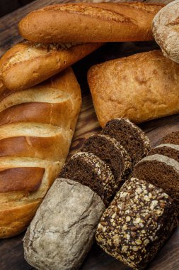 Farklı somun ekmeği un ve glütensiz buğdayla ahşap bir masada pişirilir.