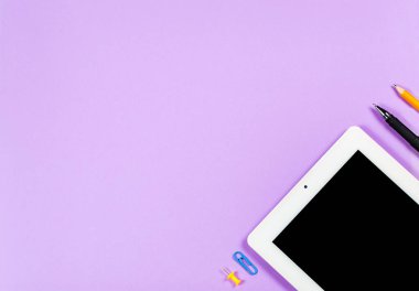 Çeşitli kırtasiye malzemeleri ve çalışma için bir telefon ve mor arka planda bir fincan kahve.