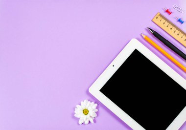 Çeşitli kırtasiye malzemeleri ve çalışma için bir telefon ve mor arka planda bir fincan kahve.