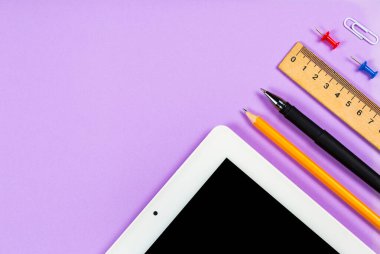 Çeşitli kırtasiye malzemeleri ve çalışma için bir telefon ve mor arka planda bir fincan kahve.