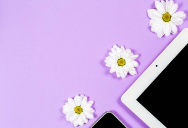 Çeşitli kırtasiye malzemeleri ve çalışma için bir telefon ve mor arka planda bir fincan kahve.