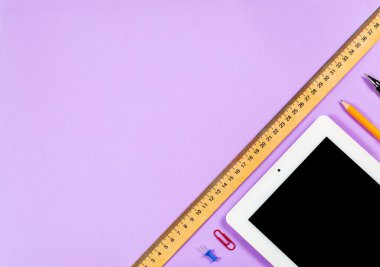 Çeşitli kırtasiye malzemeleri ve çalışma için bir telefon ve mor arka planda bir fincan kahve.