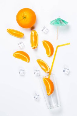 Beyaz arka planda cam bardaktaki taze portakallar.