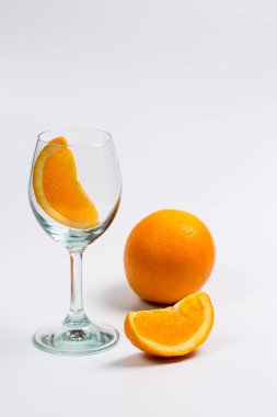 Beyaz arka planda cam bardaktaki taze portakallar.