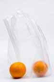 Čerstvé pomeranče v průhledném plastovém sáčku po nakupování v obchodě na bílém pozadí