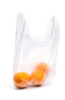 Beyaz arka plandaki bir mağazadan alışveriş yaptıktan sonra şeffaf plastik poşette taze portakallar.