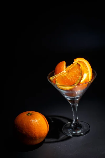 Verse Sinaasappelen Gesneden Plakjes Een Glas Een Zwarte Achtergrond — Stockfoto
