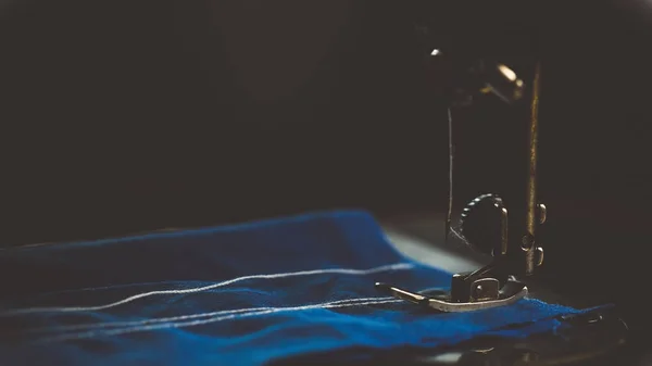 Old sewing machine, the man who sews on it, in dark colors