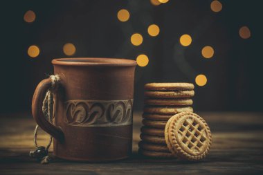 Yuvarlak tatlı kurabiyeler ve bir fincan çay eski usul ahşap bir masada.