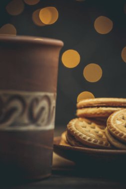 Yuvarlak tatlı kurabiyeler ve bir fincan çay eski usul ahşap bir masada.