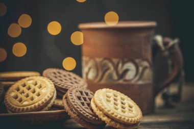 Yuvarlak tatlı kurabiyeler ve bir fincan çay eski usul ahşap bir masada.