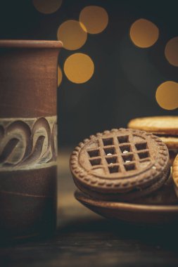 Yuvarlak tatlı kurabiyeler ve bir fincan çay eski usul ahşap bir masada.