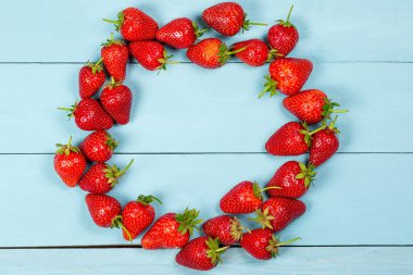 Mavi ahşap arka planda olgun kırmızı çilekler.