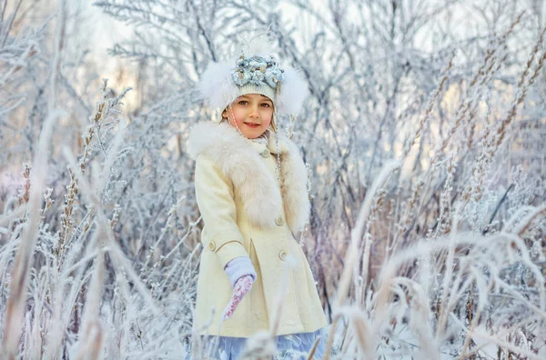 Happy adorable child girl in fur hat and coat in winter forest — Stock Photo, Image