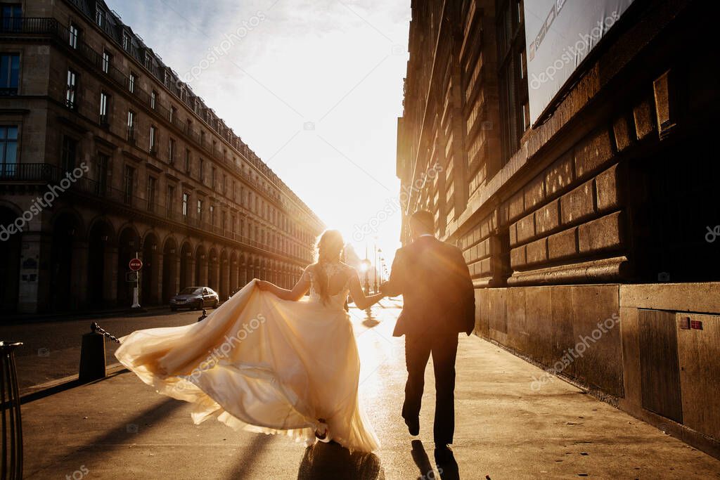 The silhouettes of a couple on a street during sunset. Wedding photo