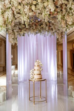 Çiçekli düğün pastası. Arka planda kemer.