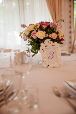 Bir restoranda düğün dekorasyonu. Çiçek kompozisyonu ile servis edilen bir masa.