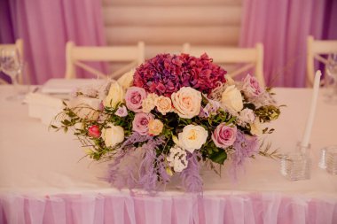 Bir restoranda düğün dekorasyonu. Çiçek kompozisyonu ile servis edilen bir masa.