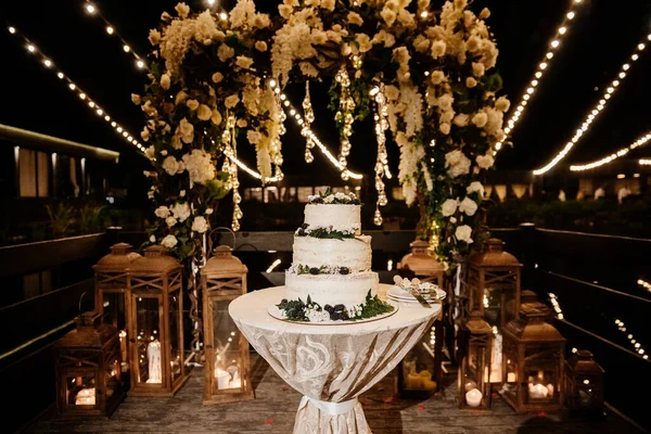 Wedding cake with arch on the background with evening lights