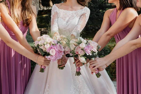 Pembe elbiseli nedimeler ve beyaz ve pembe çiçekli gelin.