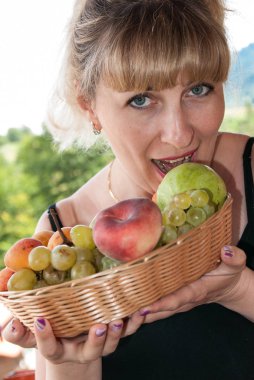 Üzüm yiyen güzel bir kızın portresi ve bir tabak meyveyle, yaklaş.