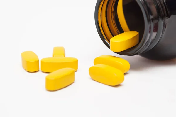 Κίτρινα Χάπια Χύνονται Από Ένα Γυάλινο Μπουκάλι Λευκό Φόντο Κοντινό — Φωτογραφία Αρχείου
