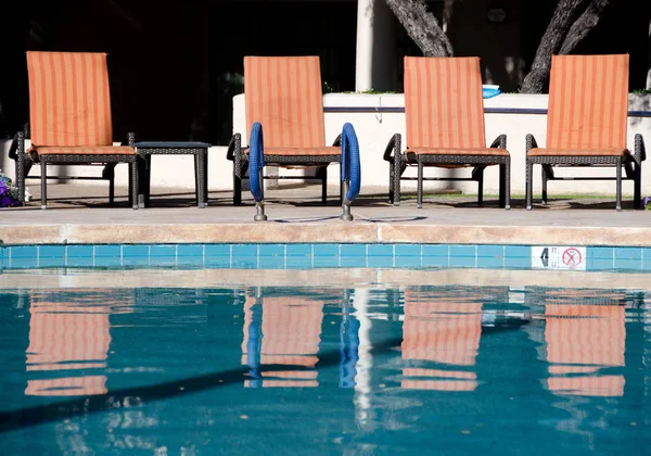 Sillas naranjas y sus reflejos en una piscina de un resort en Sco — Foto de Stock
