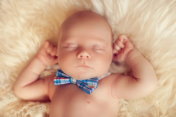 Slapen pasgeboren baby liggend met de bow tie op een witte vacht in h — Stockfoto