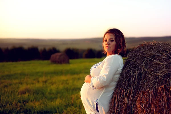 Молодая беременная женщина, стоящая рядом с Haystack на Сансет и Эмбр — стоковое фото