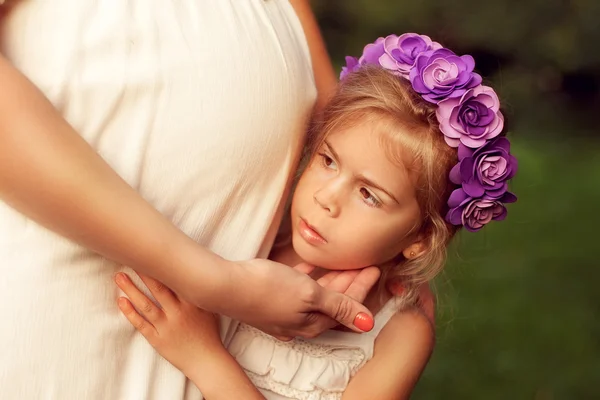 Young pregnant woman walks with her daughter. Girl hugging their — Stock Photo, Image